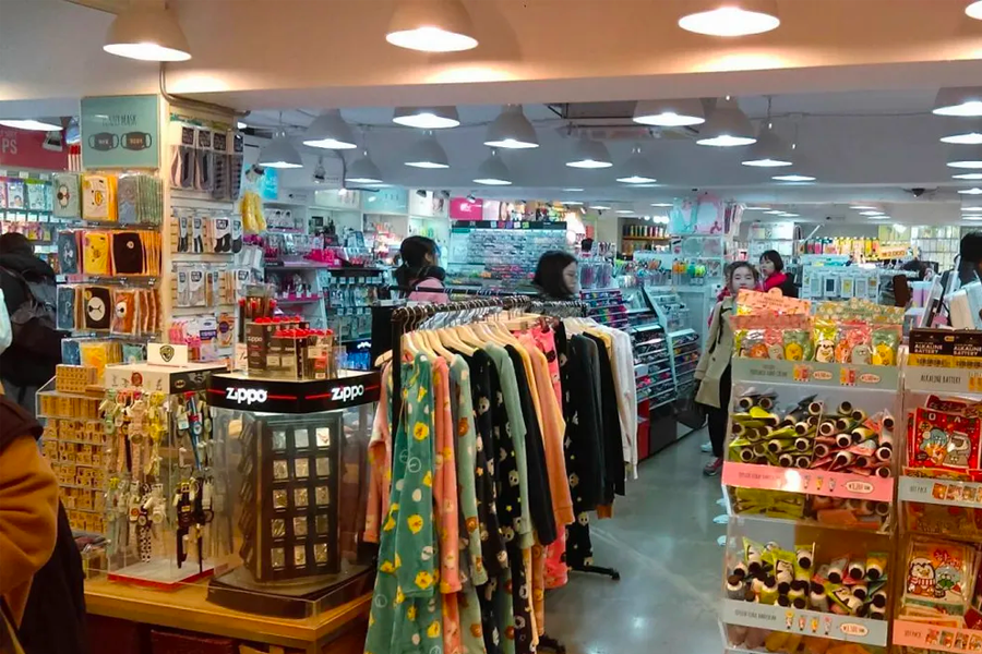 Inside view of a bustling ARTBOX store in Busan, South Korea with racks of clothing and shelves filled with stationery and cute items.