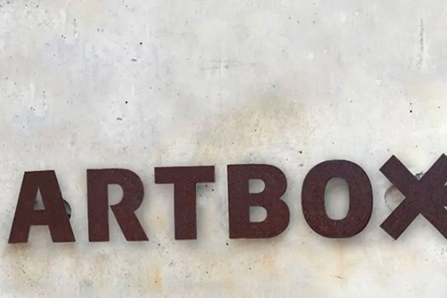 Rustic ARTBOX sign against a concrete wall, showcasing the brand's unique aesthetic.
