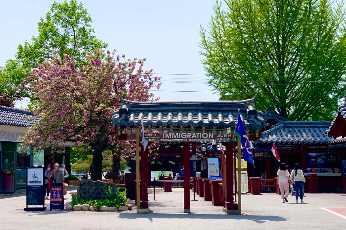 Entrance to Nami Island, showcasing the traditional Korean gate and cherry blossoms in full bloom.