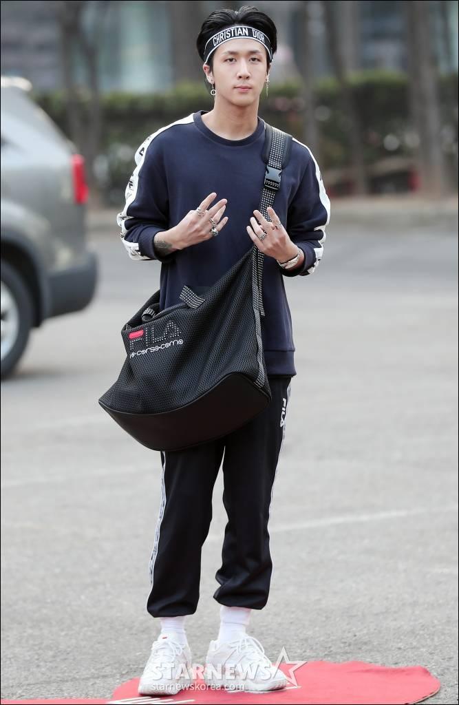VIXXのラビが黒のトレーニング服に白いスニーカーと帽子を身に着けて、KBSの「ミュージックバンク」リハーサルに参加する様子。彼は黒のショルダーバッグを肩にかけている。