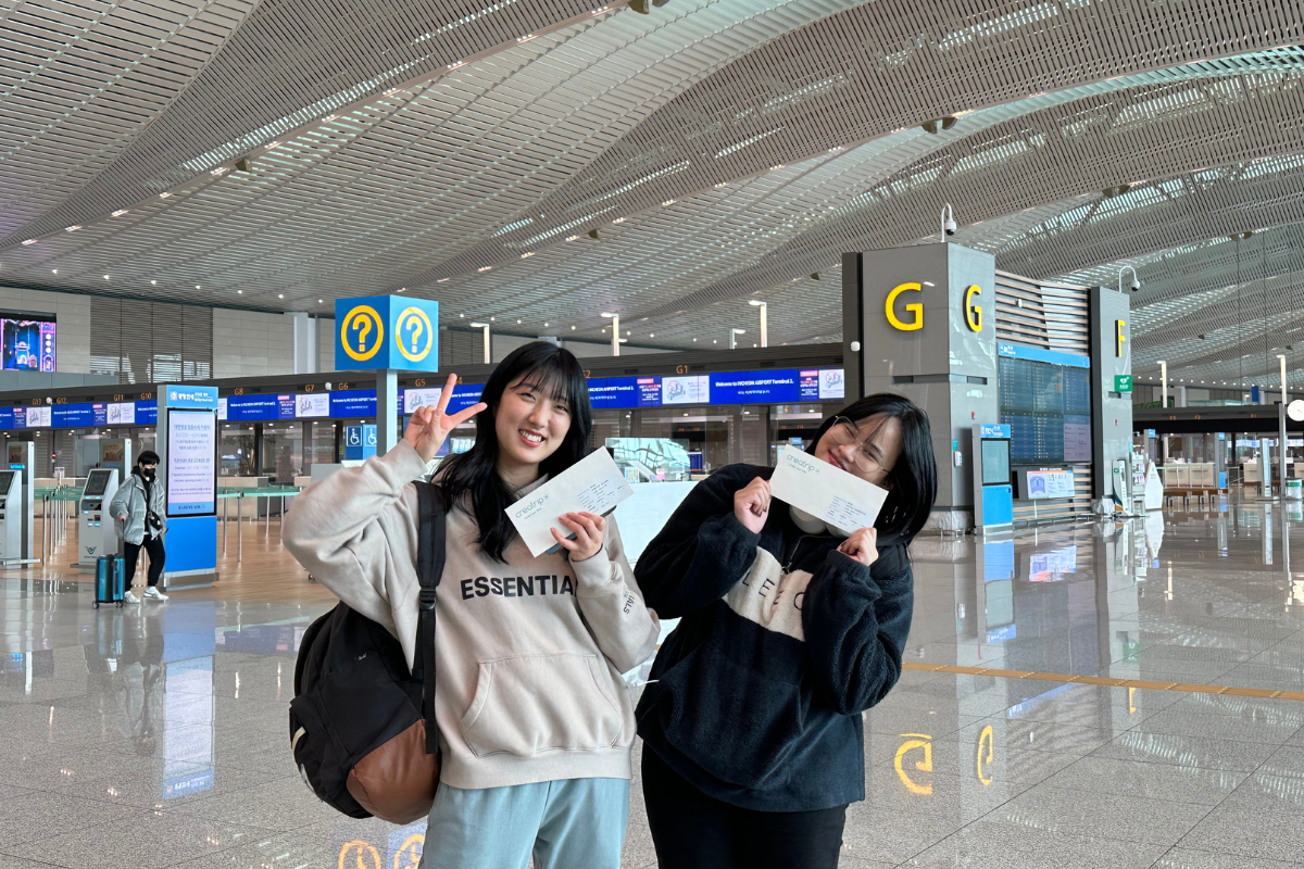 兩名乘客在機場展示創緹旅行公司的預約確認單和微笑合照