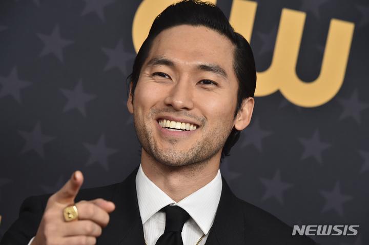 黒いスーツを着た男性、アワードセレモニーで指を指す姿