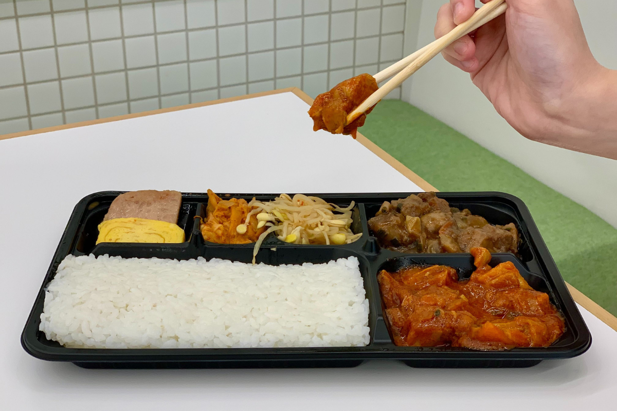 炒辣雞便當經加熱後展現濃鬱的韓式風味，配菜如芽菜及泡菜增添風味，讓人吃得滿足。