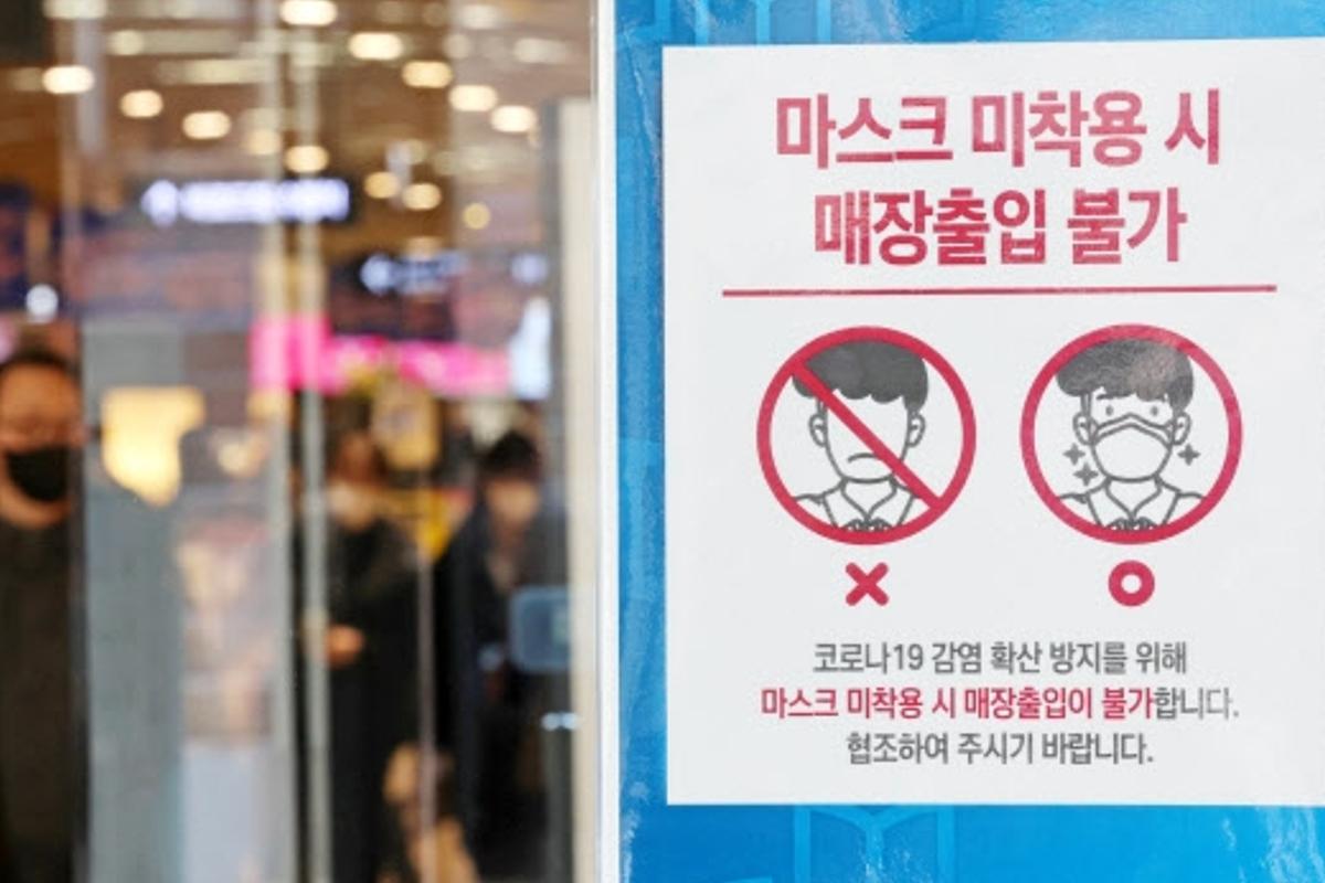 韓國一個商店的門口，展示一張用於提醒顧客佩戴口罩的標示。標示上有文字和圖示，傳達未戴口罩者不得入內的訊息。
