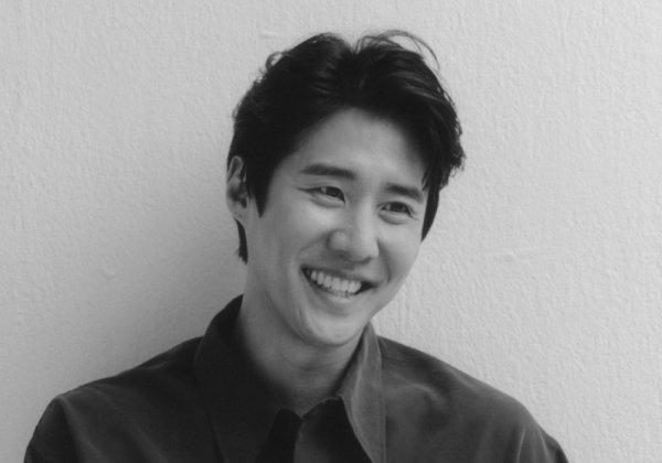 俳優ナ・チョルのポートレート写真、黒いシャツを着ている。