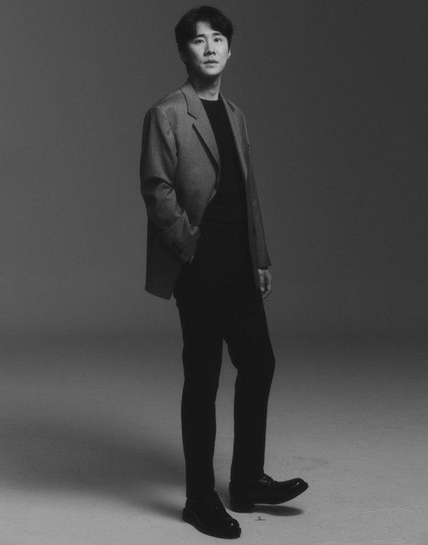 グレーのジャケットを着たナ・チョルのシックな写真。