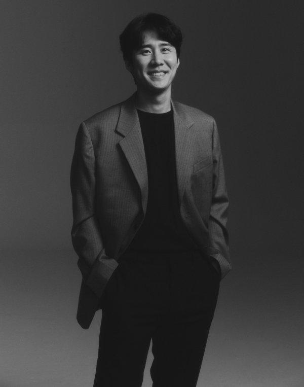 グレーのスーツを着たナ・チョルの全身写真。