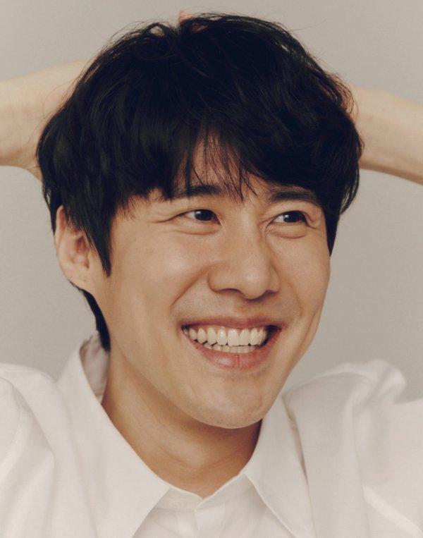 ナ・チョルのクローズアップ写真、手を頭の後ろに置いている。