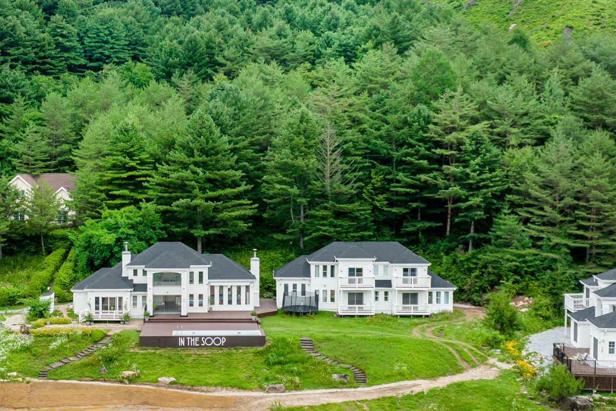 Tampilan depan kompleks rumah di 'In the Soop' Pyeongchang, dengan rumah utama dan dua bangunan tambahan.