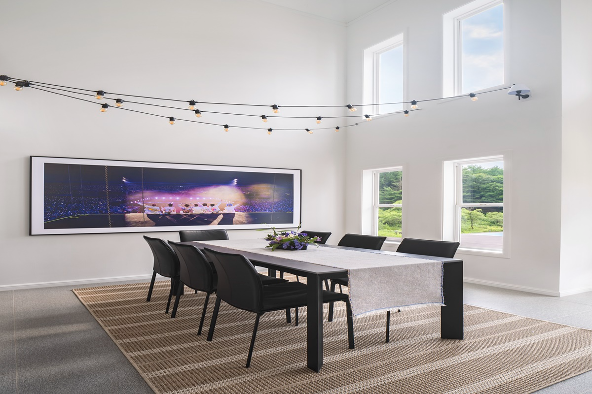 Meja makan dengan dekorasi modern di rumah 'In the Soop', terdapat bingkai gambar besar di dinding.