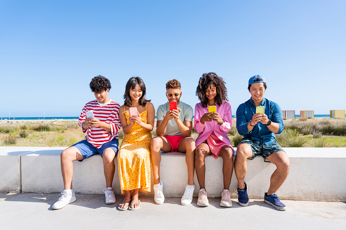 Байгалийн үзэсгэлэнт газарт гар утсаа ашиглаж буй залуучууд. Тэд тус тусдаа гар утсаа барьж, тухтай орчинд гар утасны апп ашиглаж байна.