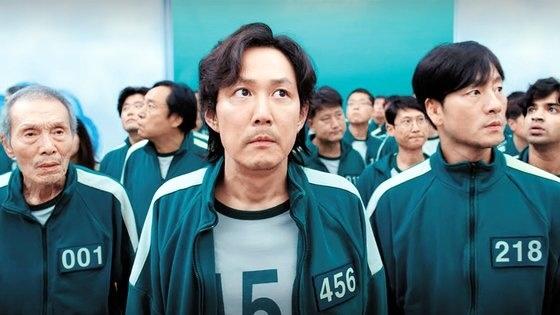 イカゲームの参加者たちが青色の運動着を身に着けて並んで立っている様子。