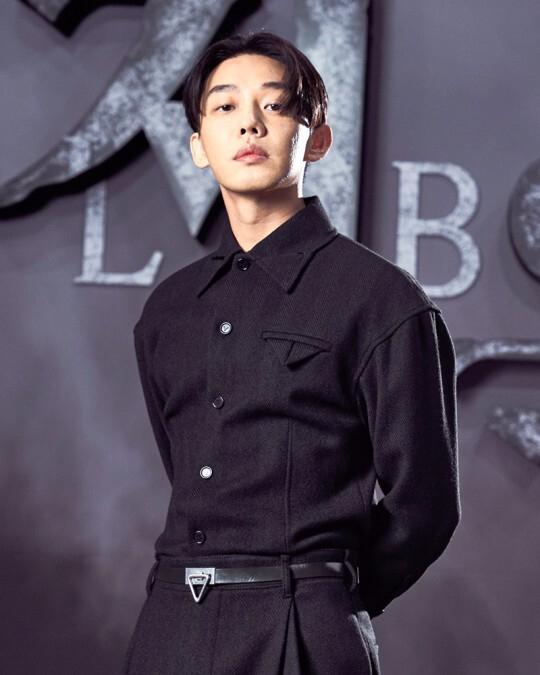 プレスイベントで黒い服を着て、ポーズをとる30代の男性俳優の姿