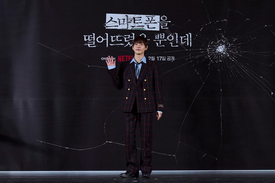 Netflix映画「スマホを落としただけなのに」の俳優イム・シワンが製作報告会でポーズをとっている様子。映画のタイトルが背景に見えます。