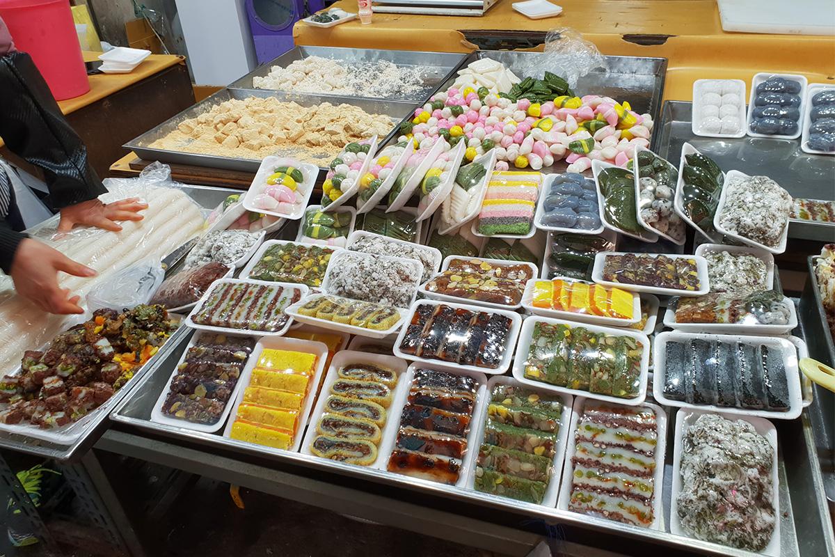 Display of assorted Korean side dishes and vegetables at Singi Market, showcasing a delicious variety of local flavors.