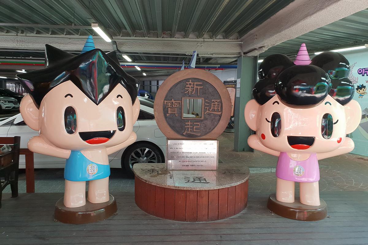 Rows of colorful market stalls and tents at Singi Market offering various goods, beneath a canopy of cherry blossom trees.