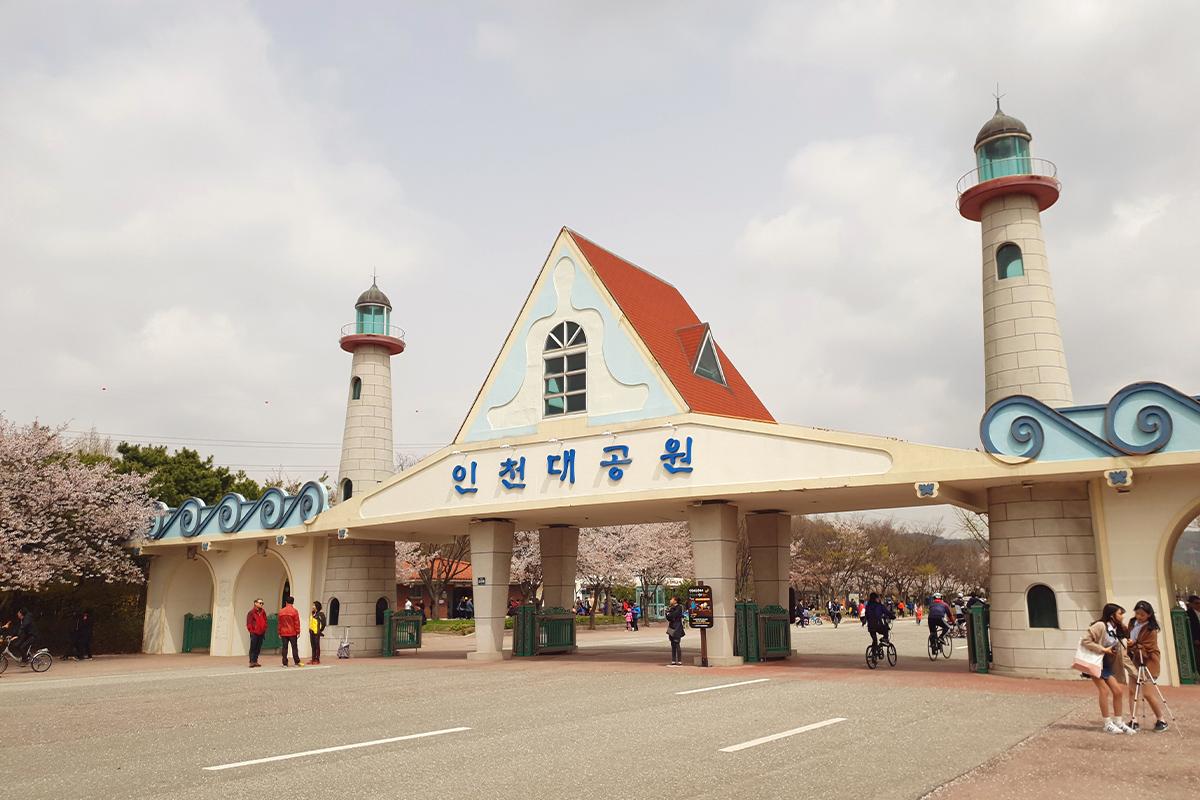 Refreshing waterfall surrounded by cherry blossoms in Wolmi Park, showcasing the harmony of nature and tradition.