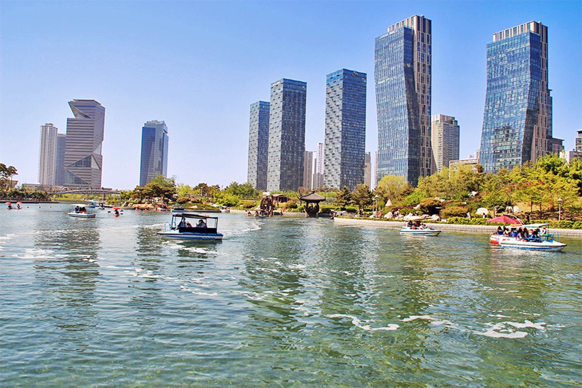 A view of cherry blossoms in front of the towering skyscraper at Songdo Central Park, merging nature with urban architecture.