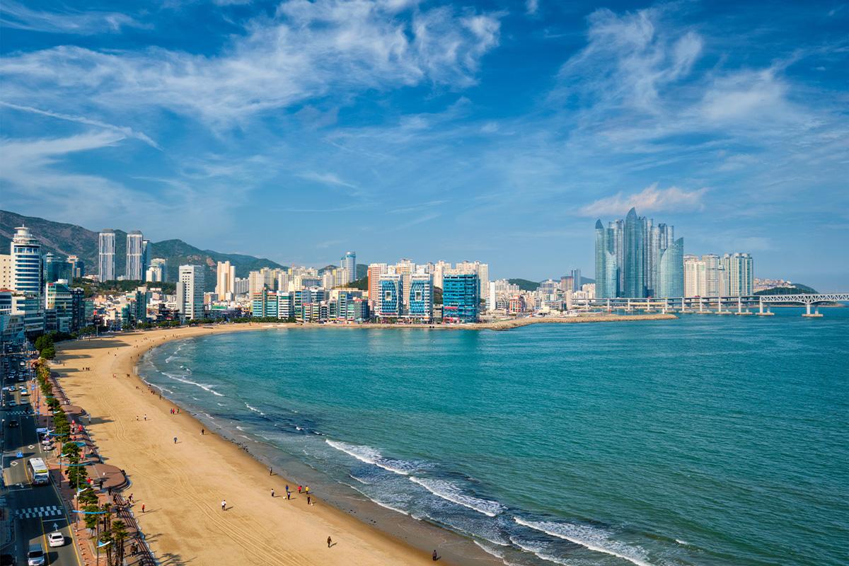Spiaggia di Haeundae a Busan, Corea del Sud, con skyline moderno e mare blu sotto un cielo sereno.