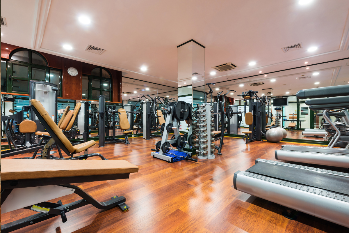 อุปกรณ์ออกกำลังกายในห้องยิมที่มีกระจกและเครื่องมือหลากหลายใช้ในการฝึกและยกเวท