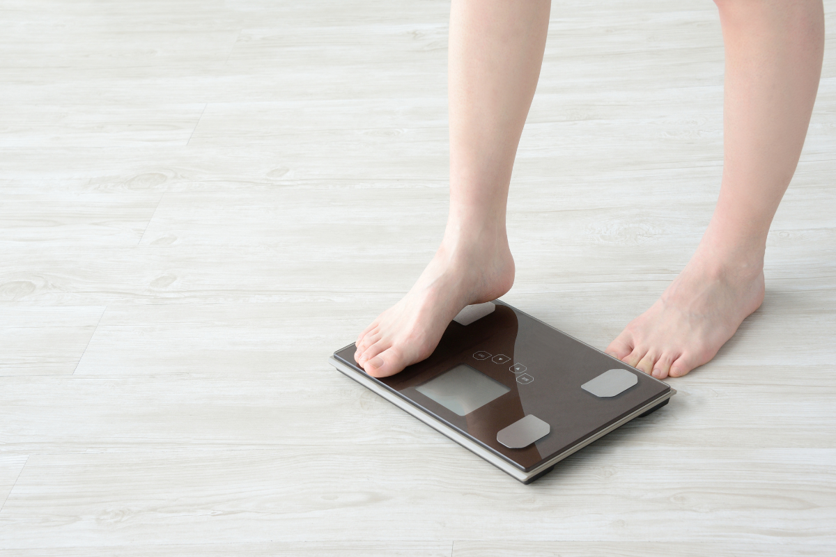 คนกำลังก้าวบนเครื่องชั่งในแผ่นดินสีขาวพร้อมการวัดผล InBody