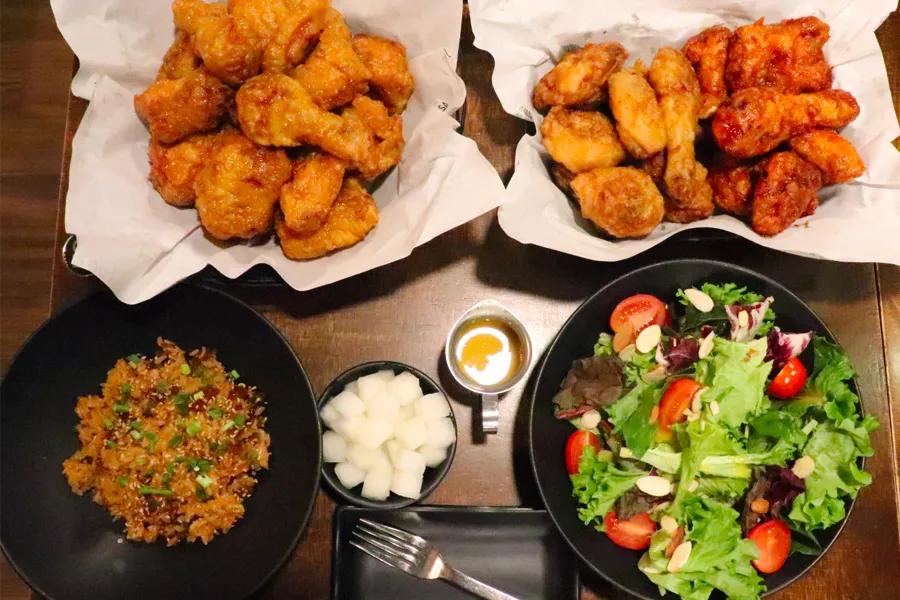 Assortment of Kyochon Fried Chicken dishes in Busan, featuring spicy and honey wings, rice, and fresh salad.