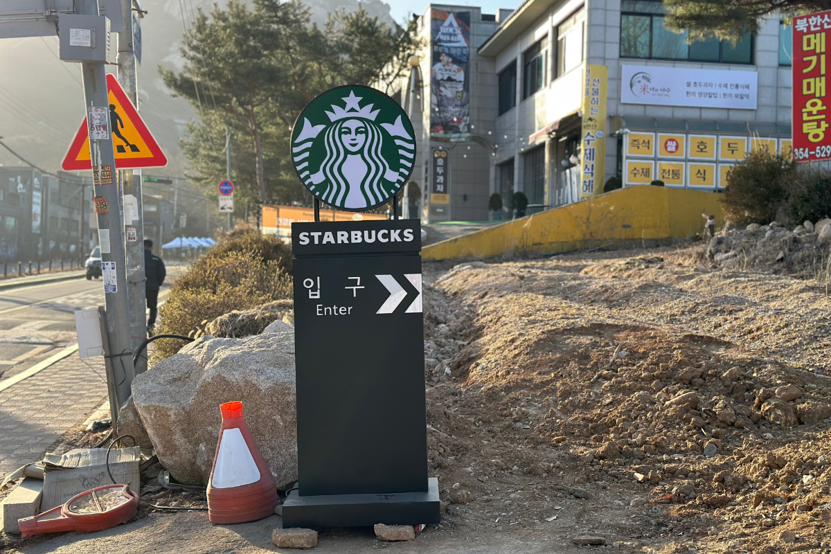 Вход с указателями к Starbucks THE Bukhansan на фоне горных пейзажей