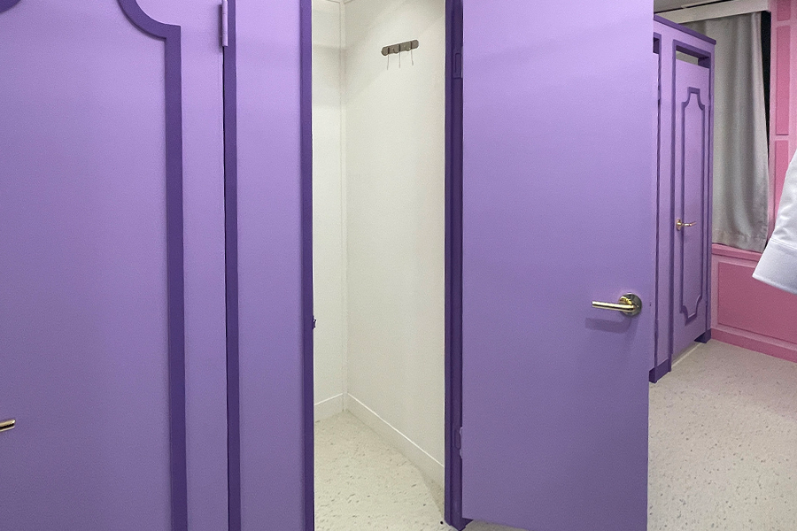 강남교복 대여점 내 설치된 보라색 탈의실 문 사진.