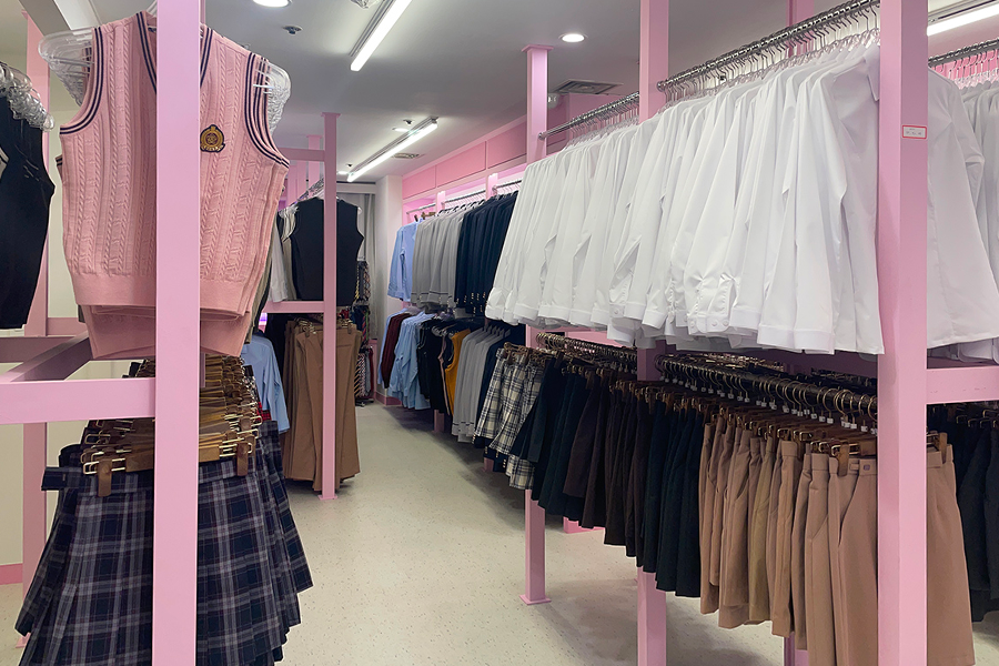 강남교복 대여점 내부에 걸려있는 다양한 색상의 교복 블라우스와 스커트.