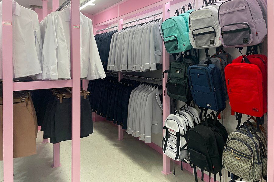 다양한 색상의 백팩과 교복이 걸려있는 강남교복 대여점 내부 사진.