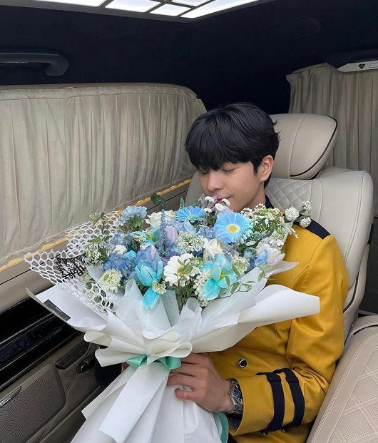 車内で花束を持つ制服姿の男性、高校の制服を着ている
