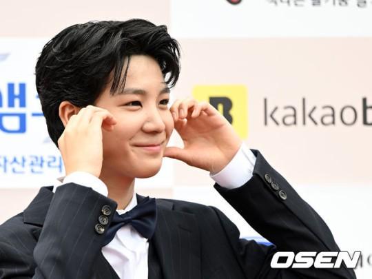 カカオの看板の前でピースサインをする男性のスーツ姿