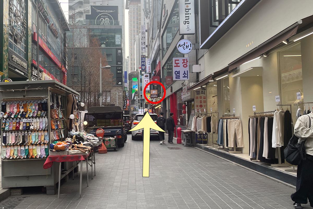 沿着韩国明洞街道的行人路线，展示出繁忙的城市生活风貌和各种商家