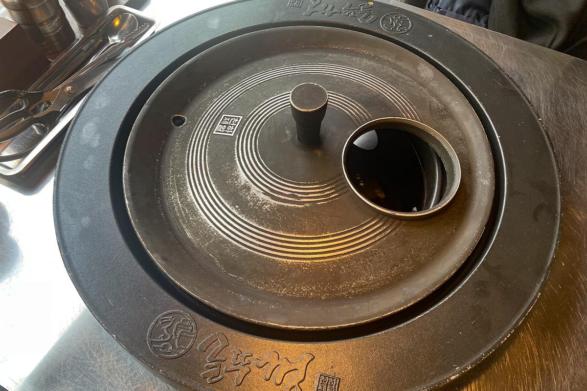 放在韩国烤肉桌上的铁锅盖，等待加热用于烤制各种食材，展现烤肉店的特色工具