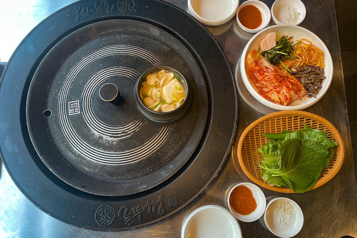 铁锅盖下的韩国豆腐汤，与烤肉和泡菜一同呈现在桌上，营造出丰富的韩国料理体验