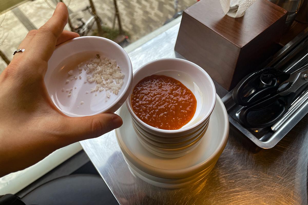 韩国烤肉桌上的调味小碟，包含包饭酱与粗盐，丰富了韩式烤肉的配料选择