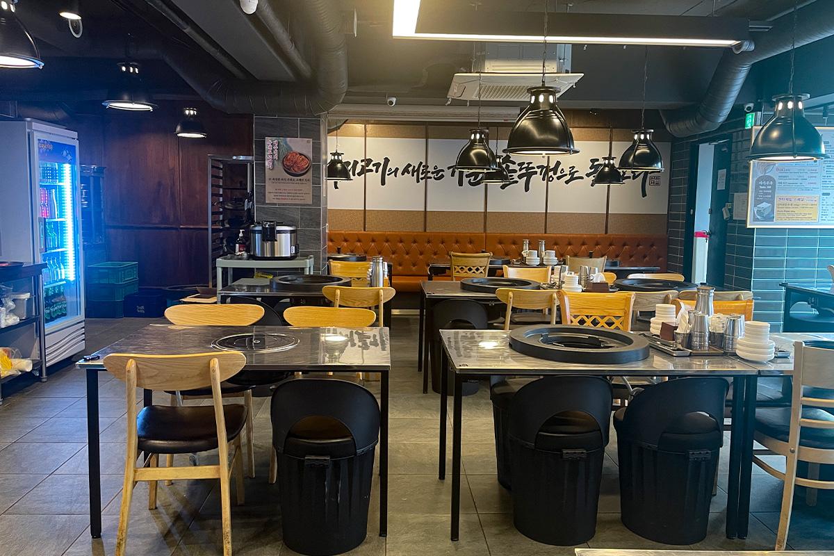 Үзэмжтэй хайруулын тавагтай шарсан махны ресторант, хоосон ширээнүүд бэлэнчлэн хүлээж байна