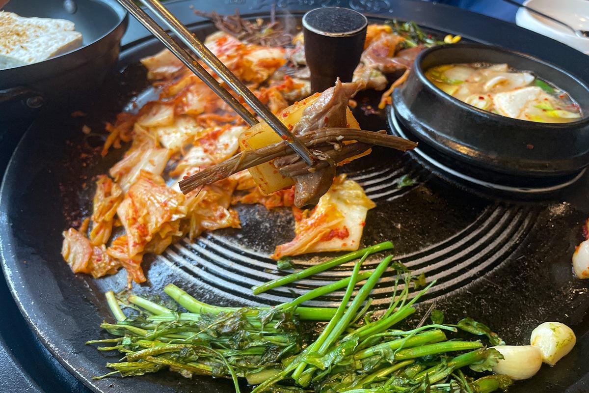 在韩国烤肉盘中烧烤的肉块，搭配不同的佐料和蔬菜吃出多元风味