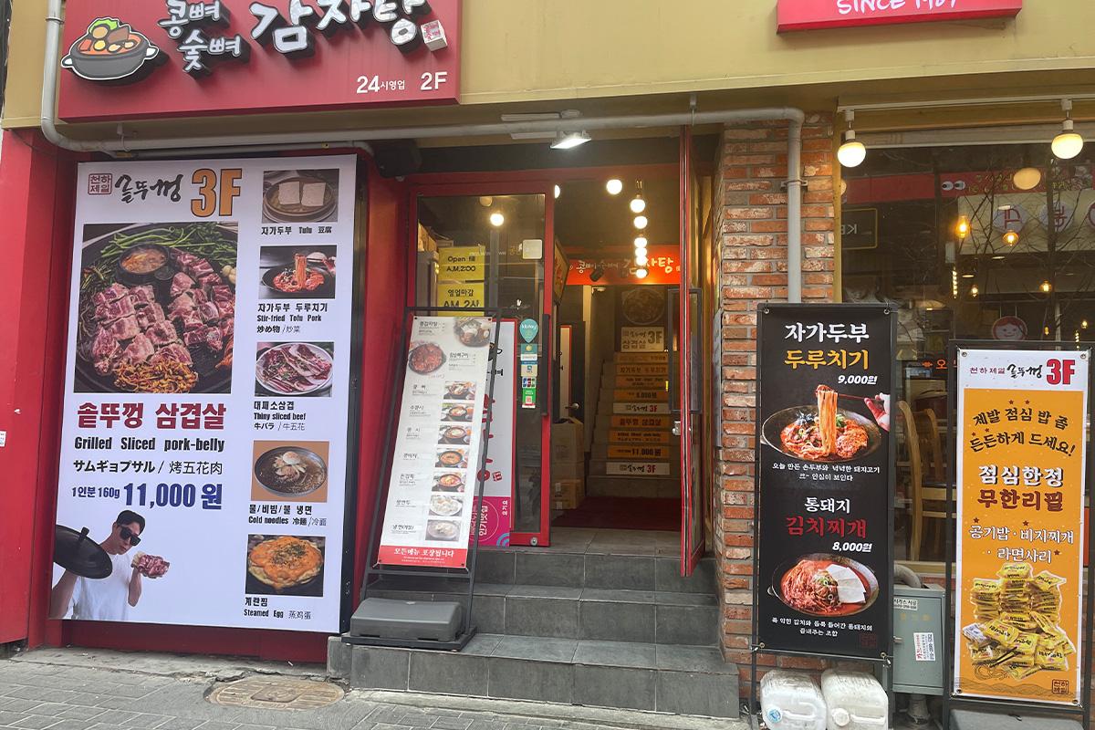 通向韩国明洞烤肉店的入口，展示出店铺招牌和楼梯方向