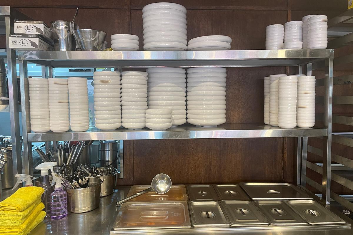 韩国明洞烤肉店厨房的盘子架，上面整齐排列着白色餐具，显示出卫生与整洁