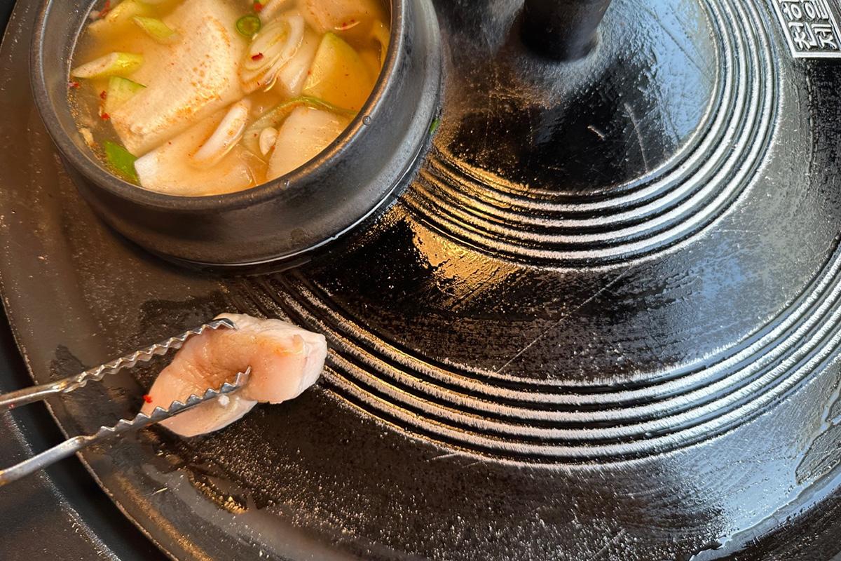 在加热的铁锅盖上，用猪油加热表面，准备进行传统韩式烤肉