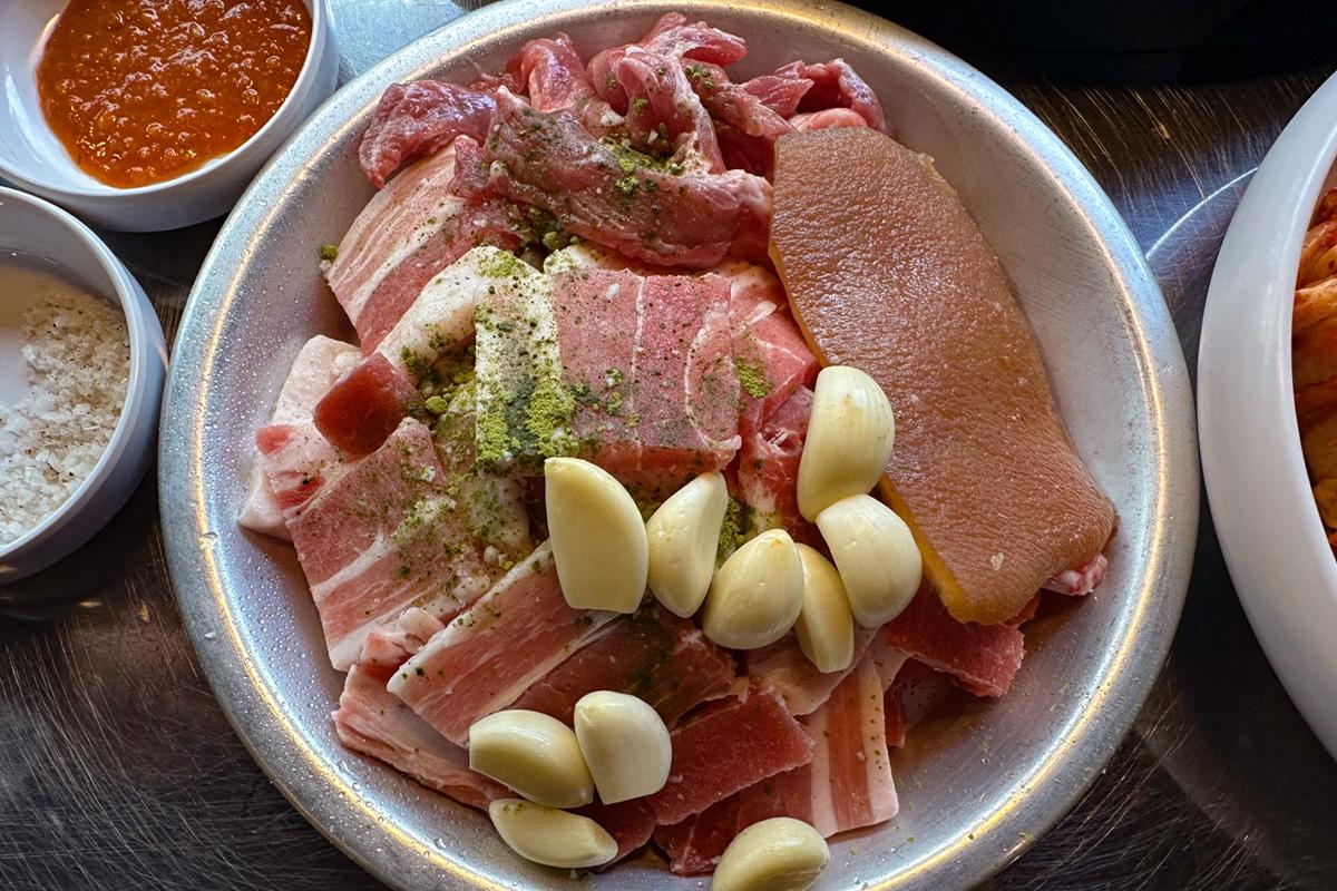 韩国明洞烤肉店的特制套餐，包括五花肉、猪排和丰富的小菜，展现了韩国料理的多样性