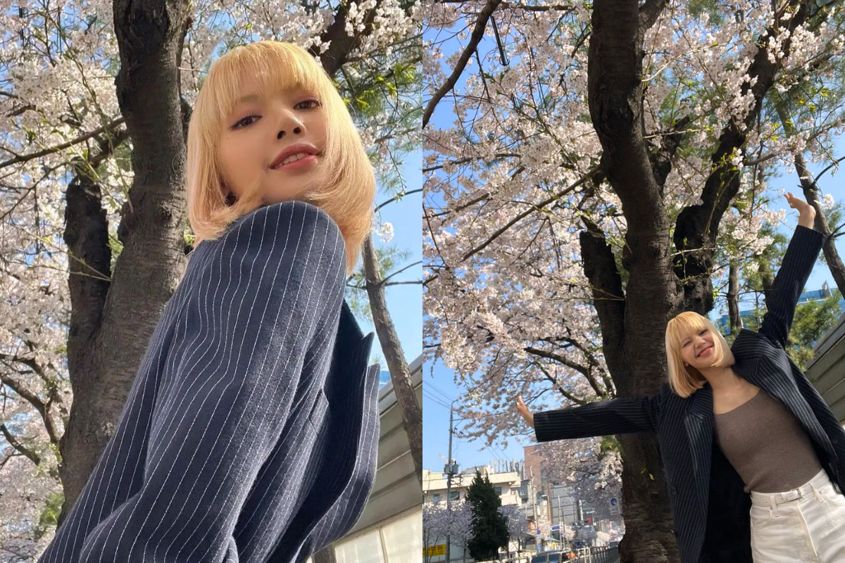 Woman wearing a pink hat and cardigan standing near cherry blossoms, highlighting the lively spring atmosphere in Korea.