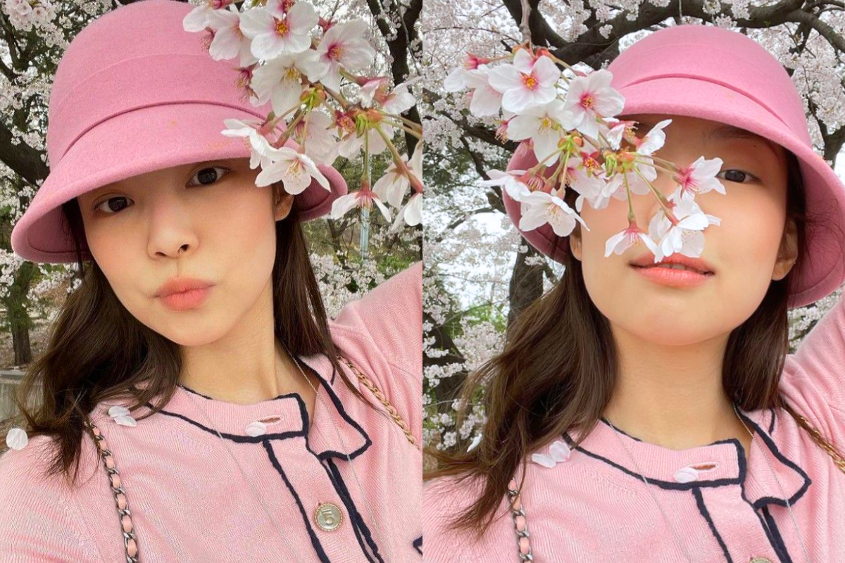 Person crouched among fallen leaves, wearing pink and posing near cherry blossoms for an aesthetic spring photo in Korea.