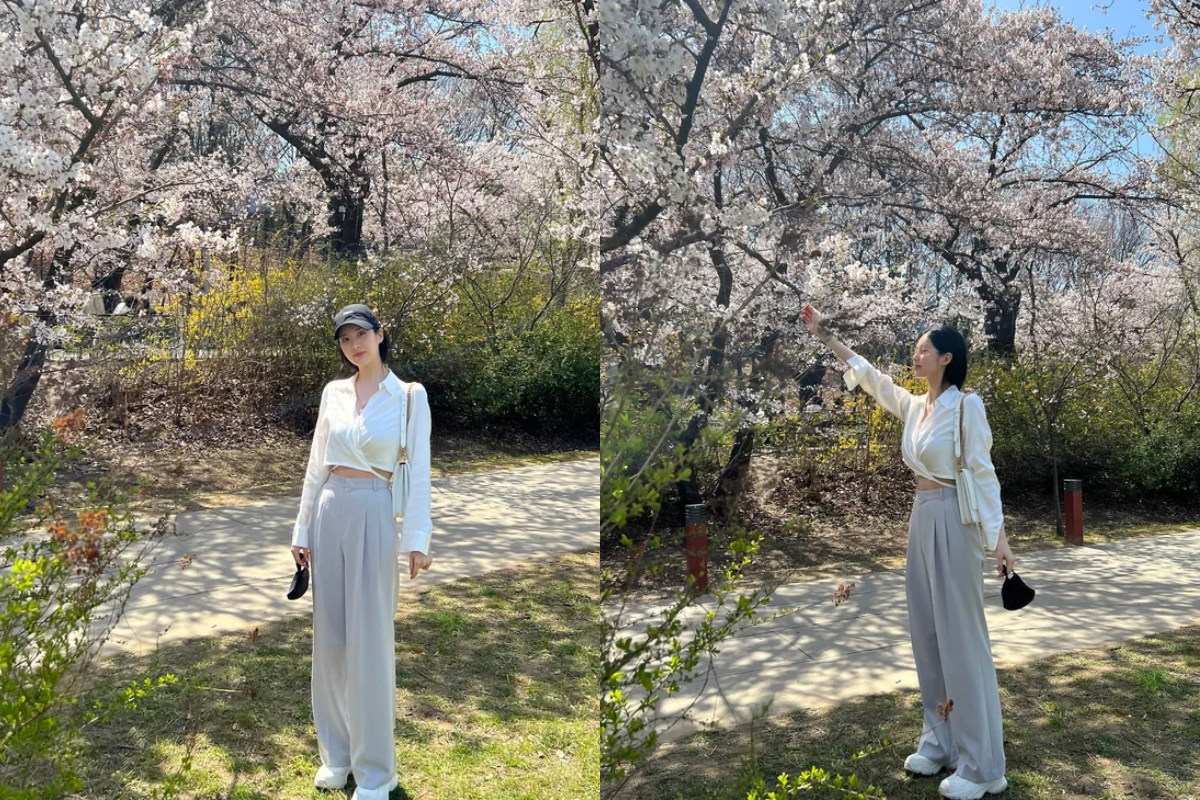 Seohyun from Girls' Generation posing under cherry blossoms, illustrating a perfect blend of fashion and nature in Korea.