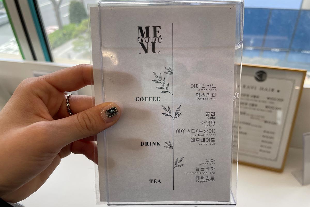 สมุดคู่มือราคาบริการของ RAVI HAIR ที่โต๊ะรับแขกและผนังพื้นหินอ่อน