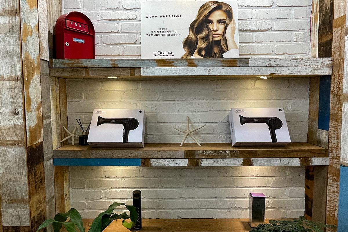 ชั้นวางผลิตภัณฑ์บำรุงผมยี่ห้อ L'Oreal และของตกแต่งภายในร้าน RAVI HAIR