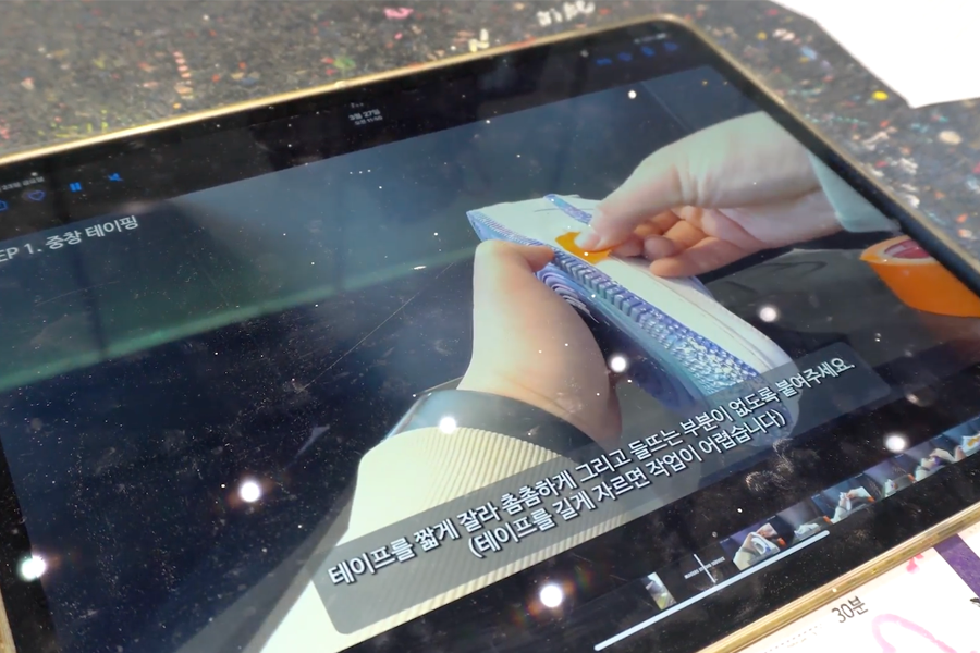 Instructional video on a tablet for taping shoes during Nike customization process