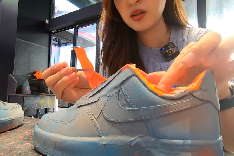 Person peeling tape off from recently spray-painted Nike sneakers
