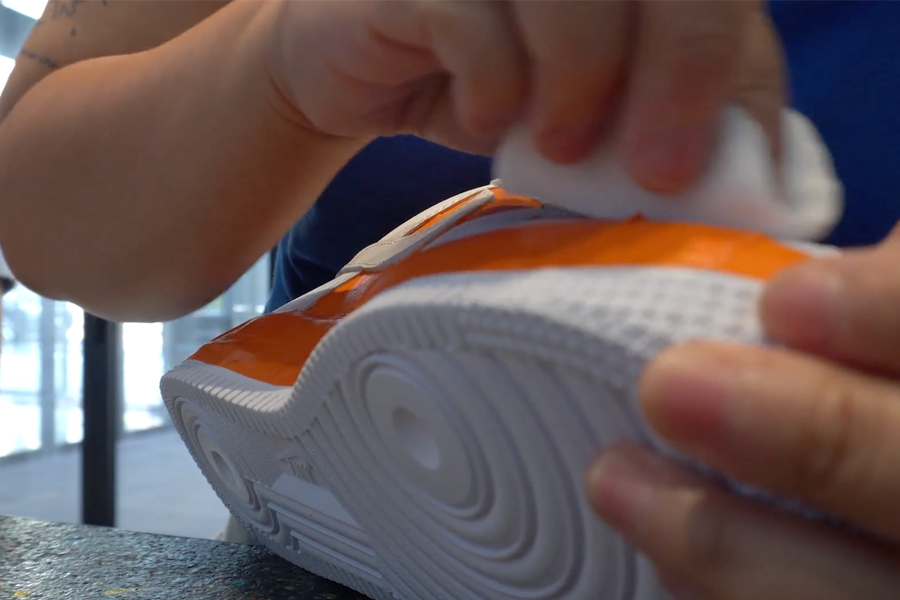 Hand cleaning the edges of a customized shoe to remove excess paint